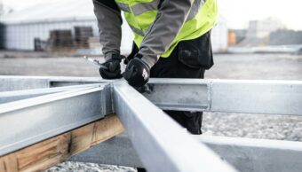 Worker assembling a steel frame structure using hand tools on a construction site