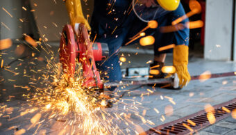 Worker cutting steel with a metal saw during industrial metal processing